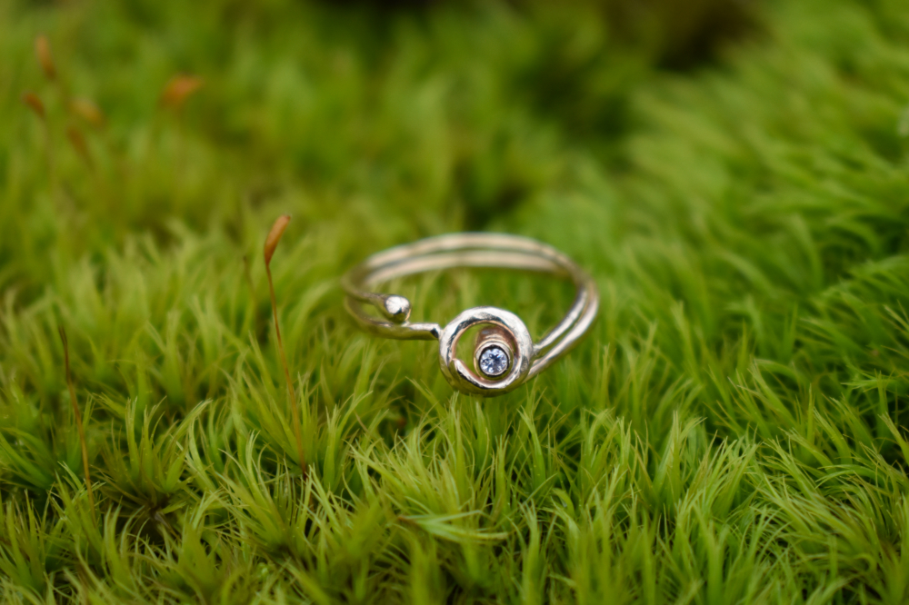 A closeup of 14k gold diamond ring sitting on a bed of moss