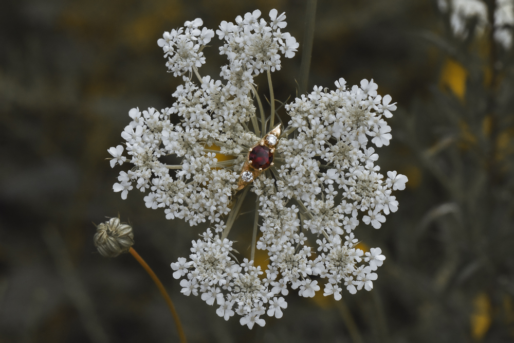 A photo of a 14k gold ring with diamonds and a garnet in a flower