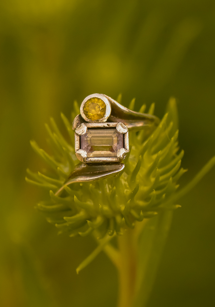 A closeup photo of a sterling silver ring with alexandrite and demantoid garnet