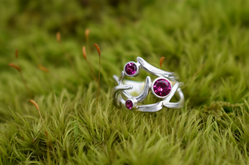 A closeup photo of an abstract sterling silver ring with rubies