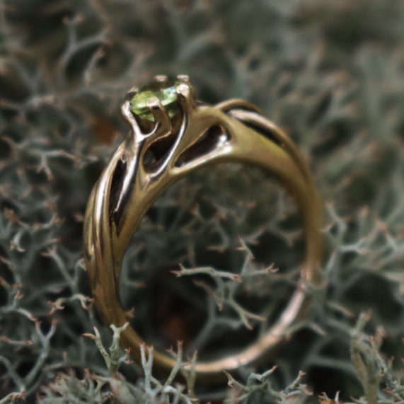 A closeup photo of a solid gold ring with peridot